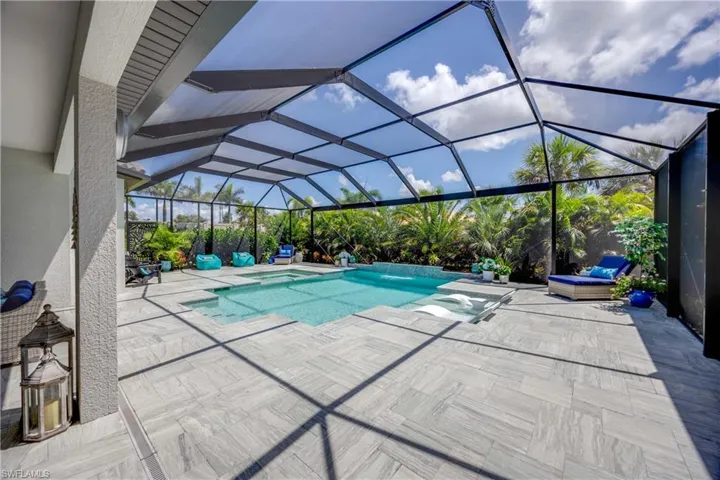 View of swimming pool with glass enclosure, an in ground hot tub, and a patio