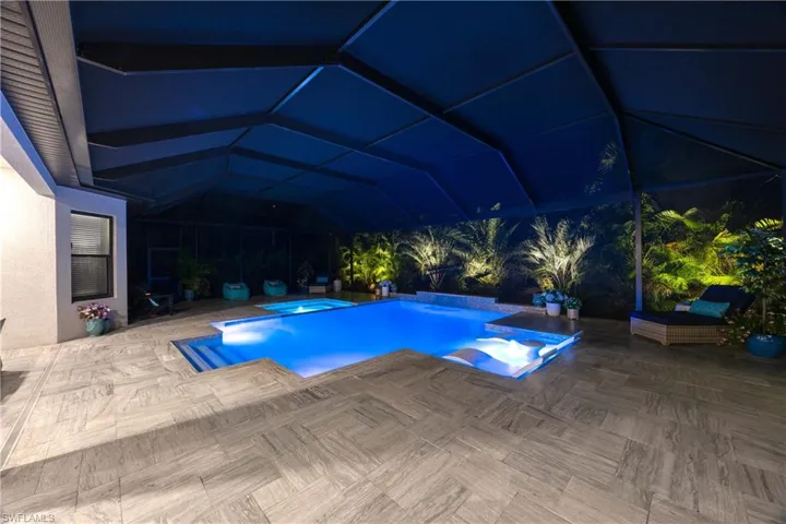 View of swimming pool featuring glass enclosure, an in ground hot tub, and a patio area