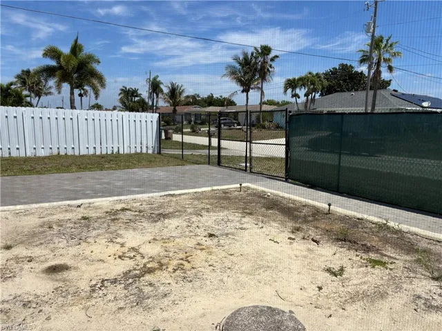 The property includes a white privacy fence, a chain-link fence with a gate, and a paver area