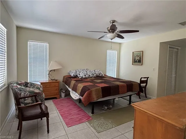 This room features tiled flooring, two windows with blinds and a ceiling fan