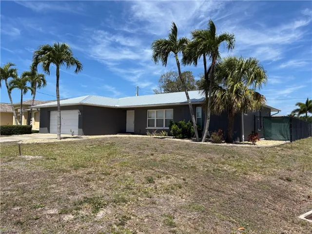 This property features a single-story residence with a light-colored roof, a neutral-toned exterior, and an attached garage