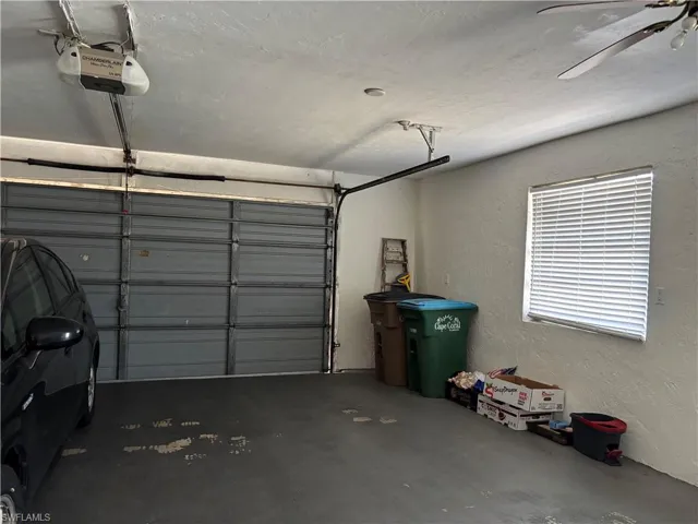 The property features a garage with a roll-up door, a ceiling fan, and a window with blinds