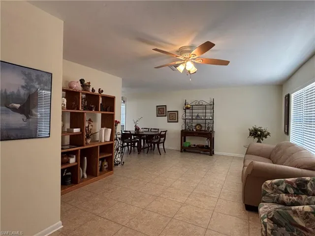 The open-concept living area features neutral-toned walls, tiled flooring, and a ceiling fan with integrated lighting