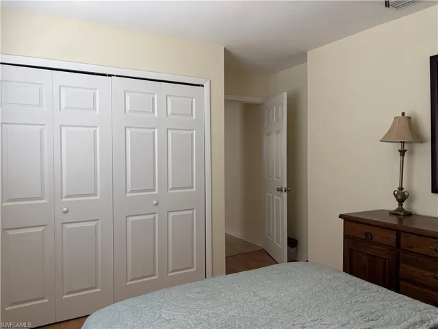 This bedroom features light-colored walls, a closet with bi-fold doors, and wood flooring