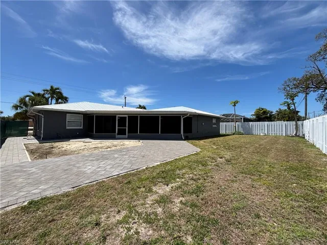 The property features a screened-in patio, a paver walkway, and a fenced yard