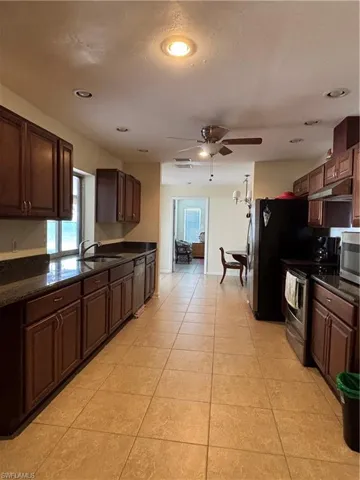 The kitchen features tile flooring, dark wood cabinetry, and recessed lighting