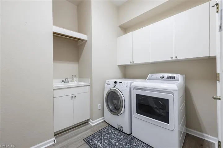 Laundry room is off the garage, with cabinets storage, a utility sink and storage closet.