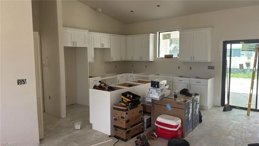 Kitchen with lofted ceiling, a kitchen island, and white cabinets