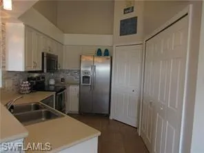 Kitchen featuring stainless steel fridge with ice dispenser, range, sink, and white cabinets