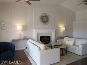 Living room featuring lofted ceiling, wood-type flooring, and ceiling fan