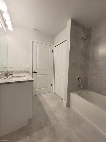 Bathroom with tiled shower / bath, vanity, and tile patterned flooring