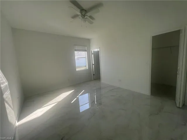 Unfurnished bedroom featuring ceiling fan, a walk in closet, and a closet