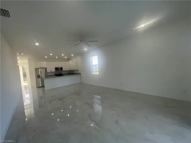 Unfurnished living room featuring ceiling fan and sink