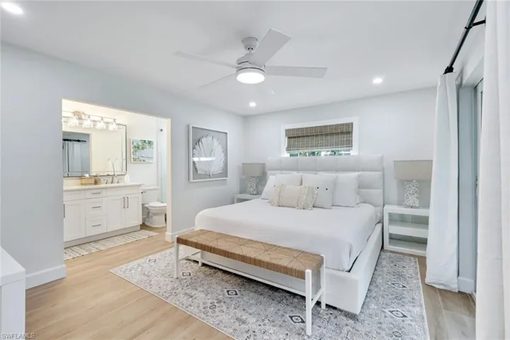 Bedroom with ensuite bathroom, baseboards, light wood-style flooring, and recessed lighting
