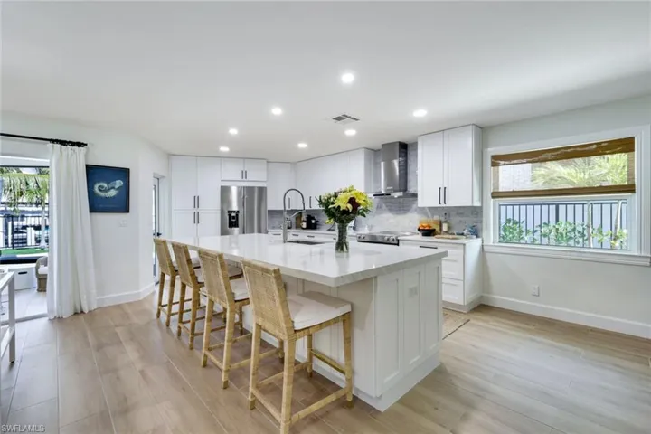 Kitchen with a sink, appliances with stainless steel finishes, wall chimney range hood, visible vents, and decorative backsplash
