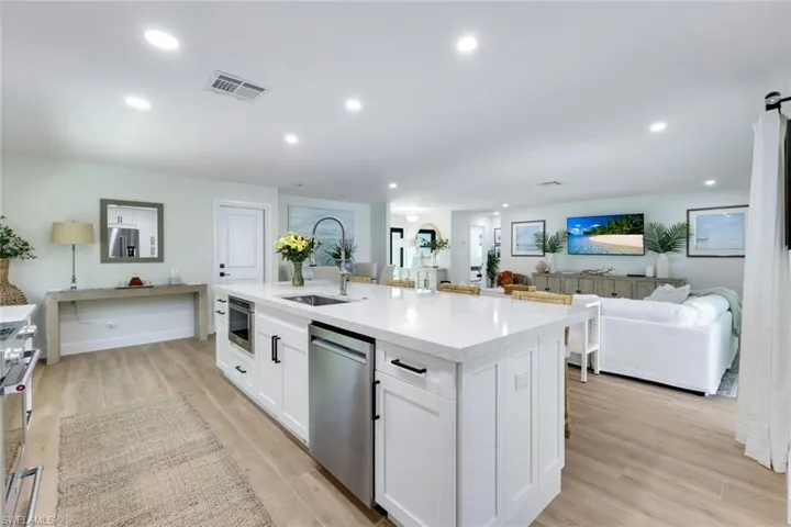 Kitchen featuring visible vents, light wood finished floors, dishwasher, white cabinetry, and a sink