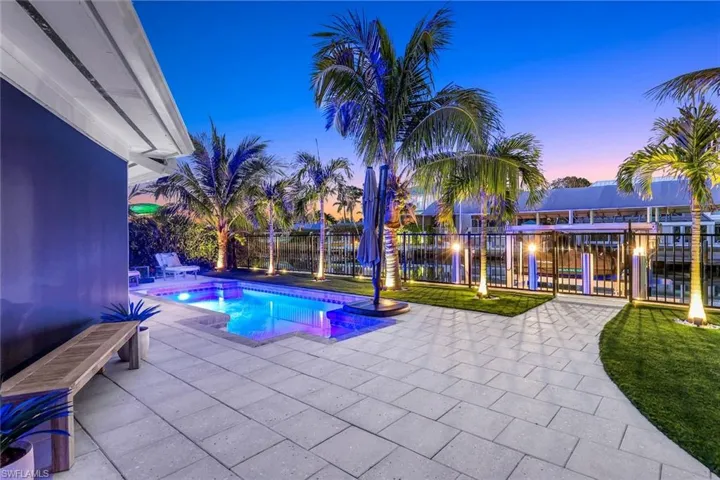 Pool at dusk with fence, a fenced in pool, and a patio area