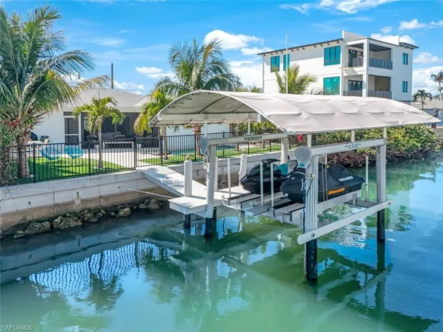View of dock featuring a water view, boat lift, and fence