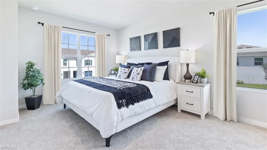 Model home. Bedroom featuring baseboards and light carpet