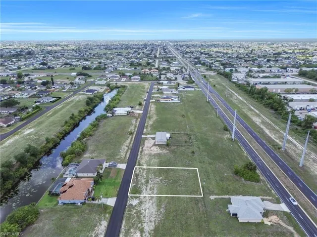 Vacant residential lot outlined in white, featuring clear ground for construction