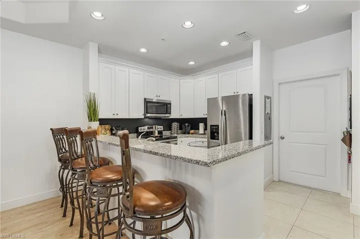 Kitchen with granite counters, a breakfast bar area, appliances with stainless steel finishes, and white cabinetry