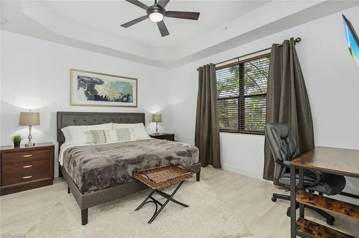 Bedroom with ceiling fan, tile wood-style flooring, and a tray ceiling