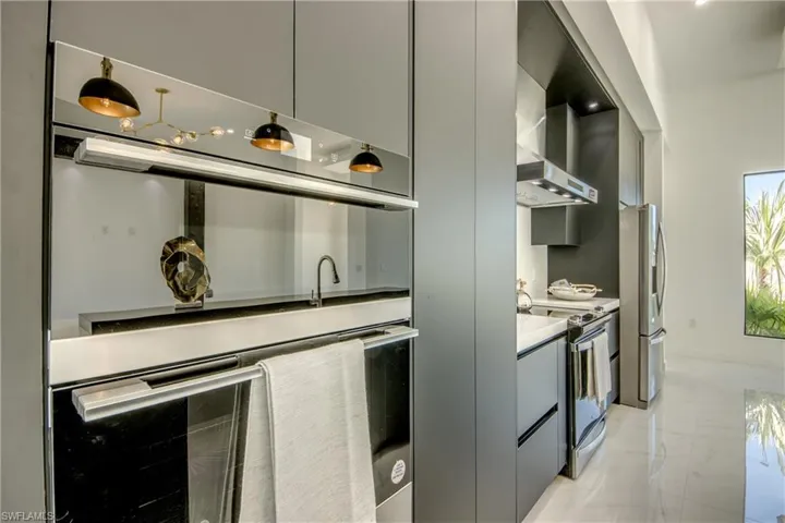 Kitchen  hood, stainless steel refrigerator, gray cabinetry, and electric stove