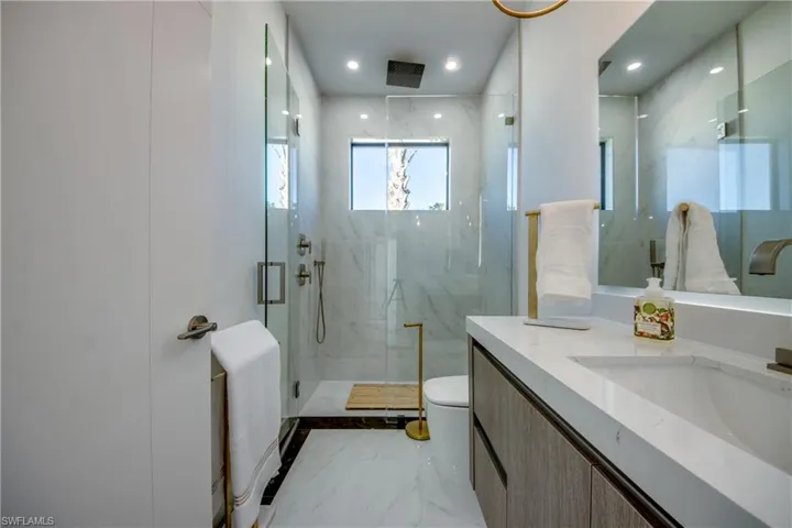 Bathroom featuring vanity, toilet, and a shower with door