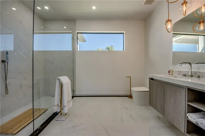 Bathroom with a tile shower, vanity, and toilet