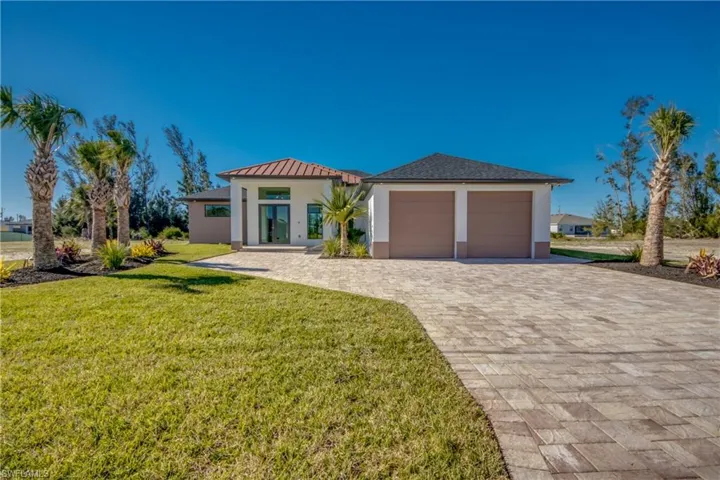 View of front of property featuring a garage and a front lawn