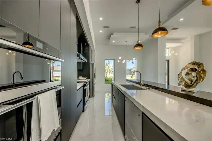 Kitchen with white range with electric cooktop, sink, stainless steel fridge, decorative light fixtures, and a chandelier