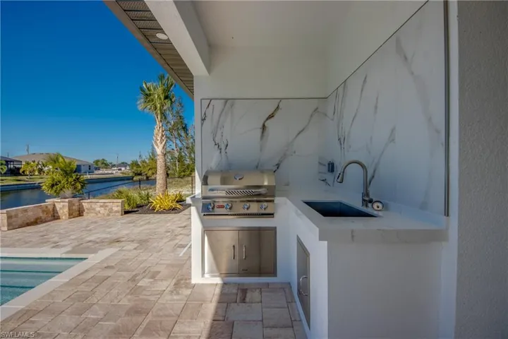 View of patio with a water view, area for grilling, grilling area, and sink
