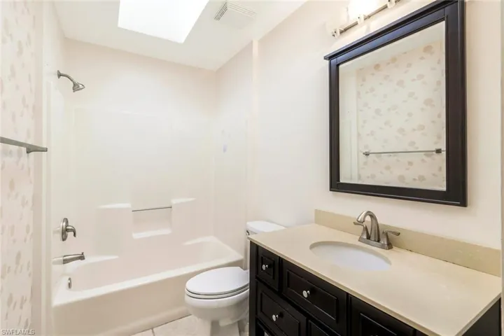 Full bathroom with vanity, tile patterned floors, tub / shower combination, and toilet