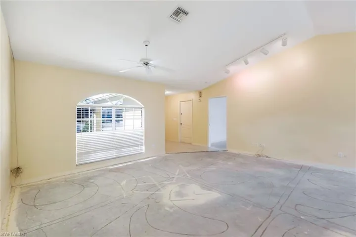 Living room featuring ceiling fan, rail lighting, and vaulted ceiling