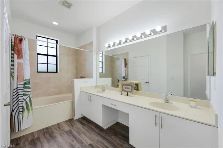 Has a combination tub and shower. With two sinks and a vanity area.