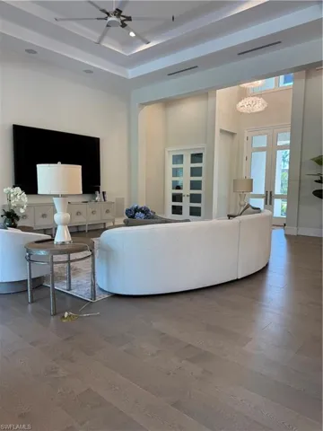 Living area with a ceiling fan, wood finished floors, visible vents, baseboards, and french doors