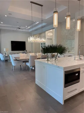 Kitchen with a sink, a tray ceiling, decorative light fixtures, and white cabinetry