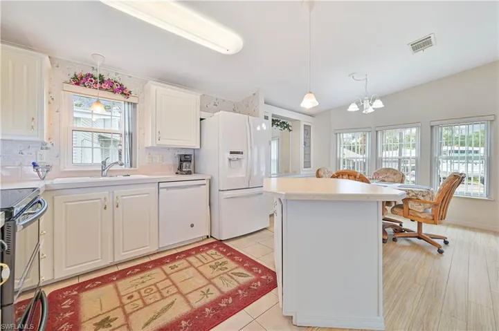 Kitchen with light tile patterned flooring, backsplash, and white appliances