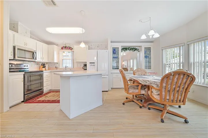 Kitchen featuring backsplash, a kitchen island, electric range oven, white refrigerator with ice dispenser, and pendant lighting