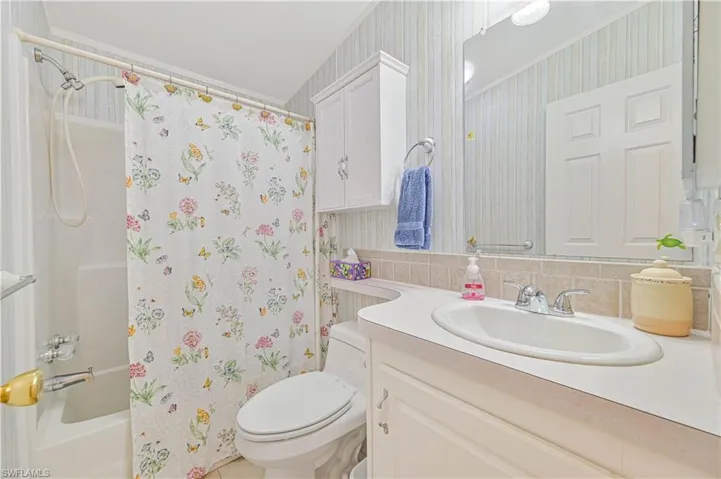 Full bathroom with toilet, shower / bath combination with curtain, tasteful backsplash, and vanity