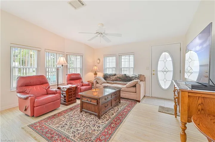 Living room with a wealth of natural light, ceiling fan, light wood-type flooring, and lofted ceiling