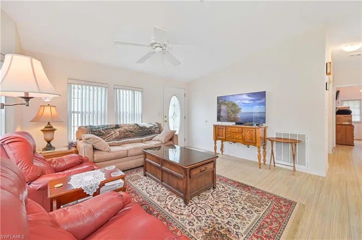 Living room featuring light hardwood / wood-style floors, vaulted ceiling, and ceiling fan
