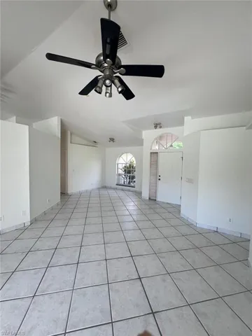 Unfurnished living room featuring light tile patterned flooring, a ceiling fan, and vaulted ceiling