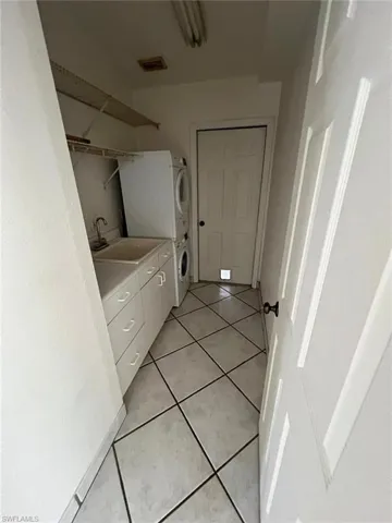 Bathroom featuring vanity, light tile patterned floors, and stacked washer / dryer