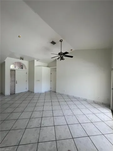 Unfurnished living room featuring vaulted ceiling, light tile patterned floors, and ceiling fan