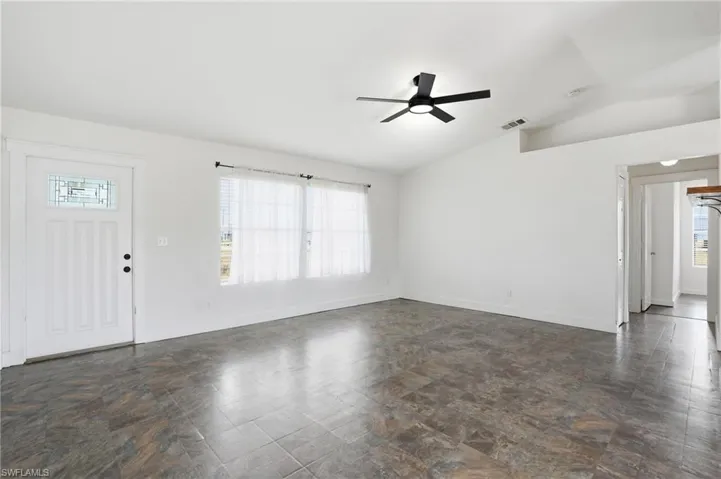 Living area featuring wood-finish flooring, a contemporary ceiling fan, and multiple windows with blinds
