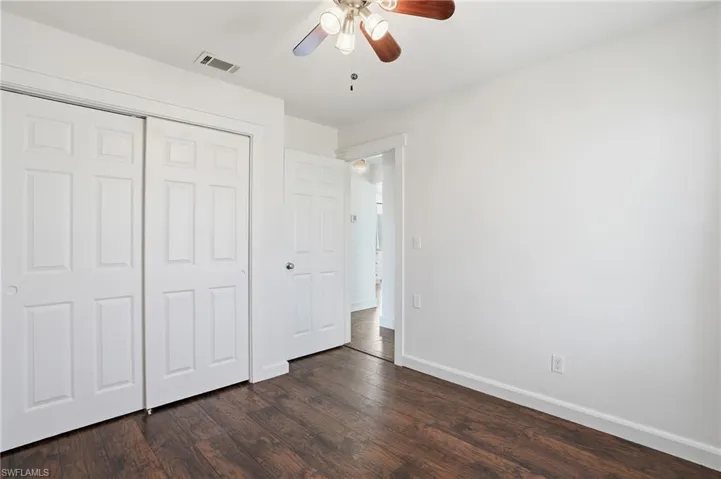 Room featuring wood-finish flooring, white walls, and a ceiling fan with integrated lighting