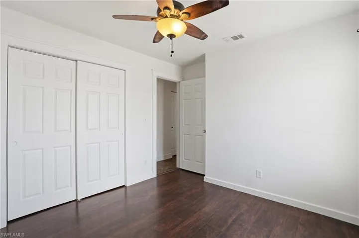 Room featuring wood-finish flooring, a ceiling fan with integrated lighting, and white walls