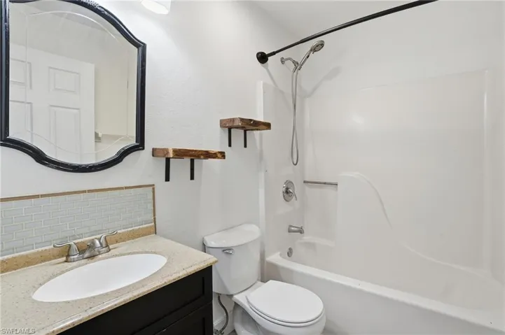 Bathroom featuring a vanity with an oval undermount sink, a light-toned countertop, and a light blue subway tile backsplash