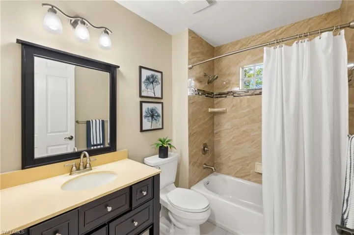 Full bathroom with toilet, shower / bathtub combination with curtain, and vanity